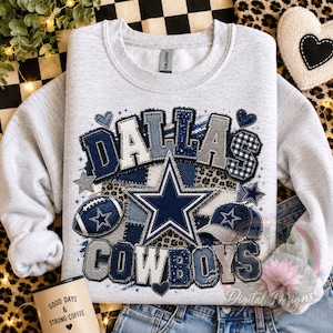Op de afbeelding: Een lichtgrijs sweatshirt met ronde hals en een grafische print met de tekst DALLAS COWBOYS. Het ontwerp bevat een grote marineblauwe ster, een football, een baseballpet en diverse patronen zoals luipaardprint en ruitjes in blauw en grijs.