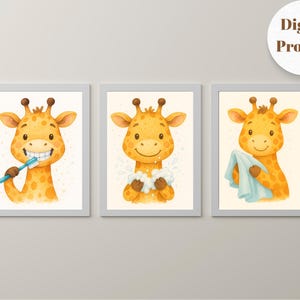 May include: Set of three framed prints featuring a cartoon giraffe. The giraffe is depicted brushing its teeth, washing with soap, and drying with a towel. The giraffe is yellow with brown spots. The prints are in a light gray frame.