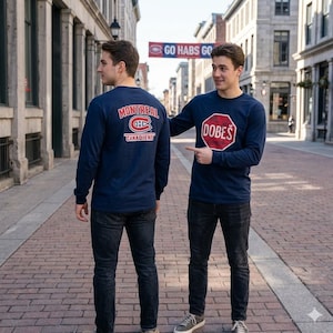Op de afbeelding: Twee marineblauwe shirts met lange mouwen. Eén toont "MONTREAL CANADIENS" met het teamlogo. De andere heeft een rode stopbord-afbeelding met de tekst "DOBES". Beide worden gedragen met een zwarte jeans.