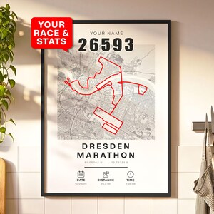 Op de afbeelding: Ingelijste print met een kaart van Dresden en een rode route die een marathonparcours markeert. De tekst "YOUR RACE & STATS" staat in een rode tekstballon. De print bevat de tekst "DRESDEN MARATHON" en racedetails.