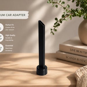 May include: A black vacuum car adapter with a long, narrow nozzle and a circular base. The text "VACUUM CAR ADAPTER" is at the top of the image. The adapter is designed to fit a vacuum and is a must-have accessory.