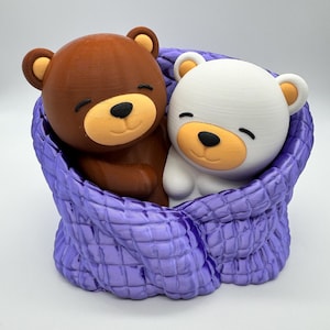 May include: A brown bear and a white polar bear cuddle inside a purple knitted blanket. The bears have closed eyes and smiling faces.