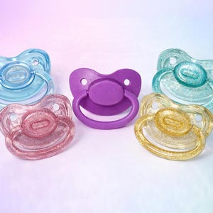 May include: A set of three ceramic mugs with a speckled, matte finish. The mugs are in shades of cream, light gray, and dark gray. Each mug has a simple, minimalist design and a rounded handle.