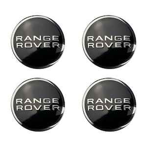 May include: Four black and silver Range Rover car emblems. Each emblem has a silver outline and the words "Range Rover" in silver lettering.