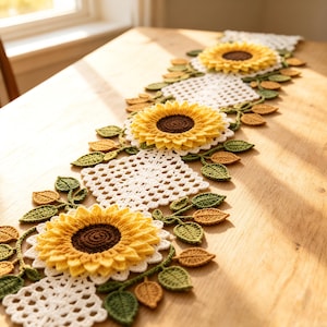 Puede incluir: Un camino de mesa de ganchillo largo y rectangular con tres grandes girasoles amarillos tridimensionales con centros de color marrón oscuro. El camino se compone de motivos de encaje blanco cuadrados y calados unidos por hojas tejidas.