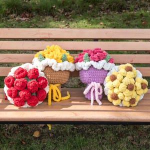 以下が含まれることがあります： 赤、黄色、ピンクなど、さまざまな色の手作りのかぎ針編みのフラワーアレンジメントのコレクション。 花はバスケットに入れられ、木製のベンチに置かれています。 かぎ針編みの作品は細かく、色は鮮やかです。