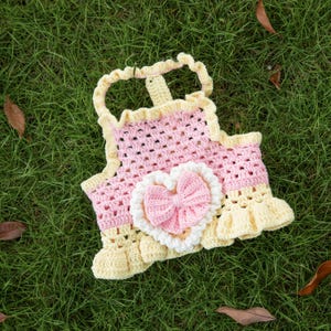 Può includere: Top per animali domestici all'uncinetto fatto a mano in rosa e giallo. Il top presenta un'applicazione a forma di cuore con un fiocco rosa e un bordo bianco. Il top ha un orlo a balze e spalline.