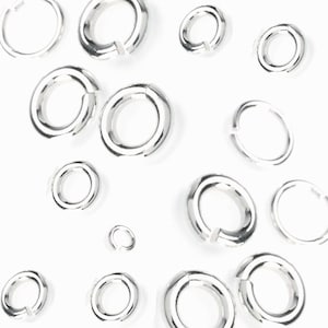 May include: A collection of silver jump rings of various sizes, scattered on a white background.