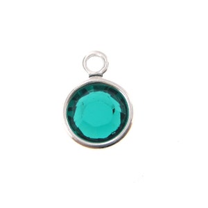 May include: A silver charm with a round, faceted, emerald green gemstone.