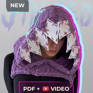 Op de afbeelding: Een dikke gebreide paarse capuchon met witte geometrische accenten en roze stiksels. De capuchon heeft een lichtblauw trekkoord. De tekst "NIEUW" en "PDF + VIDEO" zijn ook aanwezig.