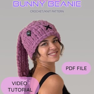 May include: A lilac-colored, chunky-knit bunny beanie with long, floppy ears. The hat features a black cross-stitch detail and a large black button. Text on the image reads "Jinxed Bunny Beanie" and "Crochet/Knit Pattern".