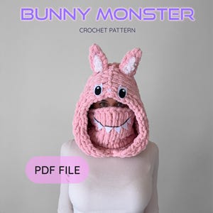 May include: A pink crocheted Bunny Monster hood with white accents and a toothy grin. The text "BUNNY MONSTER CROCHET PATTERN" is displayed above the hood. The words "PDF FILE" are in a pink rectangle below.