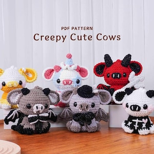 May include: Six crocheted cow plushies with a spooky theme are displayed. Each cow has unique features, including horns, wings, and different colour schemes. The text "Creepy Cute Cows" is displayed above the plushies.