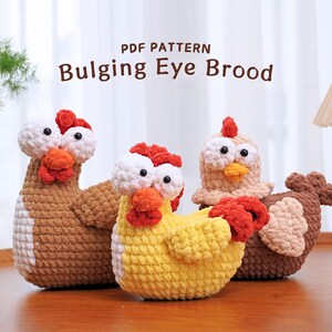 May include: Three crocheted chicken plushies with large eyes. The chickens are brown, yellow, and beige. The plushies are sitting on a wooden surface. The text "PDF PATTERN Bulging Eye Brood" is displayed above the plushies.