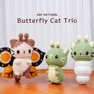 May include: Three crocheted cat figures. One is a butterfly cat with brown, white, and black wings. The other two are green cats. The text "PDF PATTERN" and "Butterfly Cat Trio" are at the top of the image.