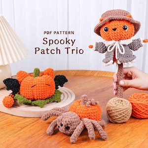 May include: A collection of handmade crochet Halloween decorations, including an orange pumpkin with bat wings, a brown spider, and a scarecrow figure. The text "Spooky Patch Trio" is visible.
