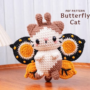 May include: A handmade crochet Butterfly Cat doll with a white, brown, and cream body, black eyes, and pink cheeks. The doll has large butterfly wings with black, yellow, and orange details. The text "PDF PATTERN Butterfly Cat" is visible.