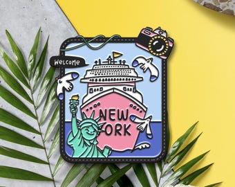 May include: A colorful New York themed patch with a cruise ship, Statue of Liberty, and camera. The patch has the word "Welcome" and "New York" on it. The background is blue, pink, and yellow.