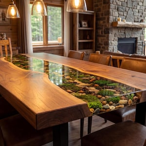 May include: A large wooden dining table with a river-like design. The table features a live edge and a clear resin center filled with stones, moss, and plants. Brown leather chairs surround the table, creating a rustic and natural aesthetic.