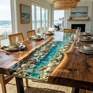 May include: A rectangular dining table featuring two live-edge wood slabs separated by a central river of clear blue resin filled with various seashells and starfish. The table is set with white plates, bowls, and clear wine glasses.