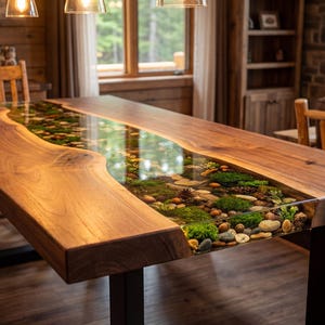 May include: A handcrafted wooden dining table with a clear resin river running through the center. The river is filled with stones, moss, and small plants. The table is supported by black metal legs and measures approximately 96 inches long.