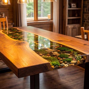 May include: A handcrafted wooden dining table with a clear epoxy river running through the center. The river is filled with stones, moss, and greenery. The table has a natural wood grain finish and black metal legs. The table is approximately 96 inches long.