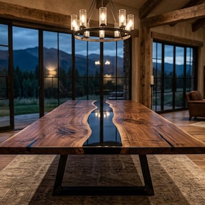 May include: A large rectangular dining table featuring two thick slabs of natural wood with a live edge, separated by a central strip of smooth black resin. The table is supported by a black metal frame base with angled legs.