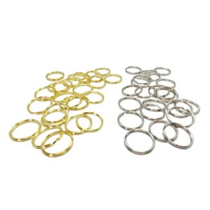 Peut inclure: Un assortiment de porte-clés fendus de couleur or et argent. Les anneaux de porte-clés sont ronds et en métal. Les porte-clés dorés sont à gauche et les argentés à droite, sur fond blanc.