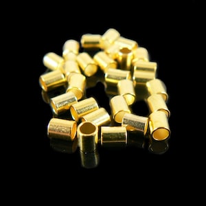 May include: A group of gold-colored metal crimp beads, used for jewelry making.