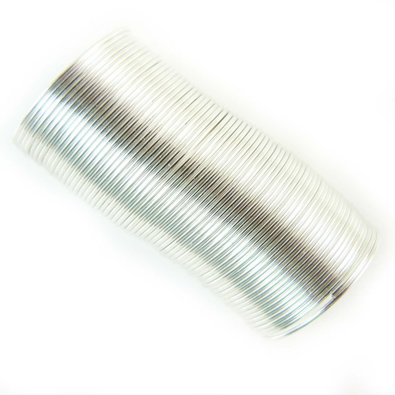May include: A silver coil of wire, tightly wound into a cylindrical shape. The wire is shiny and reflective, creating a metallic look.