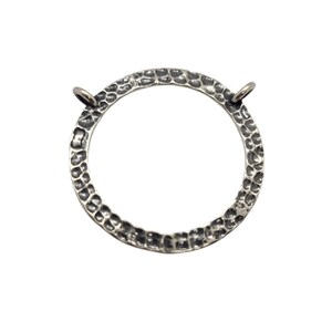 May include: A silver circle pendant with a hammered texture and two jump rings. The pendant is about 2 inches in diameter.