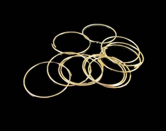 May include: A group of gold-colored metal hoops of varying sizes, arranged in a loose pile on a black background.