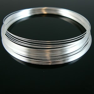 May include: A roll of silver-coloured wire, coiled into a circle. The wire is thin and shiny, and it is ideal for jewellery making or other crafts.