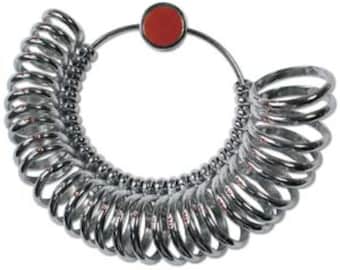 May include: A silver ring sizer with a red button. The sizer has a series of rings of different sizes.