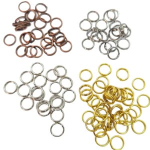 May include: A collection of small metal rings in copper, silver, and gold. The rings are all the same size and shape, and are likely used for jewellery making or other crafts.