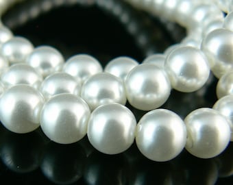 May include: A strand of white pearl beads, arranged in a circular pattern, with the pearls reflecting light.