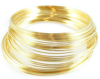 May include: A stack of gold-colored wire rings, each ring is slightly smaller than the one below it.