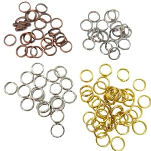May include: An assortment of small metal rings in four different colors: copper, silver, and gold. The rings are all the same size and shape, and are likely used for jewelry making or other crafts.