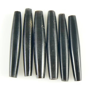 May include: Six dark, elongated wooden beads with a tapered shape. The beads are a deep, rich brown color and have a smooth, polished finish. They are arranged in a row against a white background.