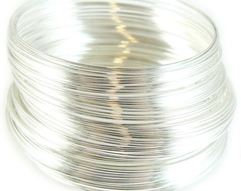 May include: A stack of silver wire rings, each ring is thin and smooth. The rings are stacked on top of each other, creating a cylindrical shape.