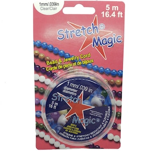 Puede incluir: Un rollo de cordón elástico transparente para cuentas y joyería. El cordón tiene un diámetro de 1 mm y una longitud de 5 metros. El embalaje es rosa y blanco con el texto "Stretch Magic" en letras grandes.