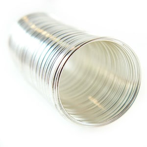 May include: A stack of silver rings, tightly wound together, creating a cylindrical shape. The rings are smooth and shiny, reflecting light.
