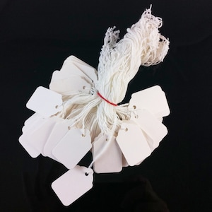May include: A bundle of white string with a red string tied around it. The string is attached to a large stack of white blank gift tags.