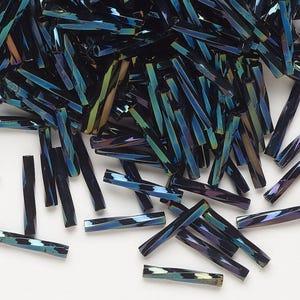 May include: A pile of iridescent dark blue glass beads, each bead is a long, thin, rectangular shape.