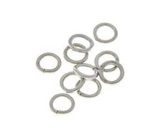 May include: A group of silver jump rings, a type of jewelry finding used for connecting chains, cords, and other jewelry components.