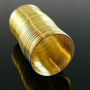 May include: A close-up of a gold-coloured coil of wire. The wire is tightly wound and has a shiny, metallic finish.