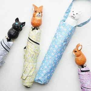 May include: Four colorful umbrellas with animal-shaped handles. The umbrellas are closed and feature floral patterns in yellow, blue, and pink. The handles are a fox, a cat, a polar bear, and a rabbit.