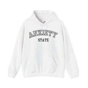 May include: White hooded sweatshirt with the text "ANXIETY STATE" in black outlined letters.