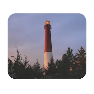 Peut inclure: Un phare rouge et blanc avec une lumière au sommet, entouré d'arbres sur un fond de ciel bleu.