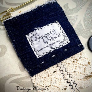 Puede incluir: Una etiqueta artesanal de mezclilla y encaje con el texto "Designed by Nina at Tatters to Treasures". La etiqueta est&aacute; asegurada con un imperdible dorado. La parte inferior de la etiqueta presenta encaje color crema con una costura en zigzag.